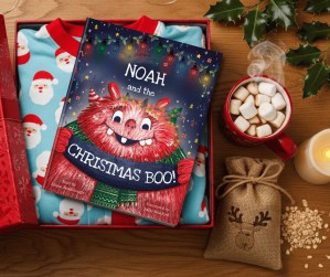 An open Christmas Eve box with a Tickled Moon 'Christmas BOO!' personalised for Noah on top of Christmas pyjamas.